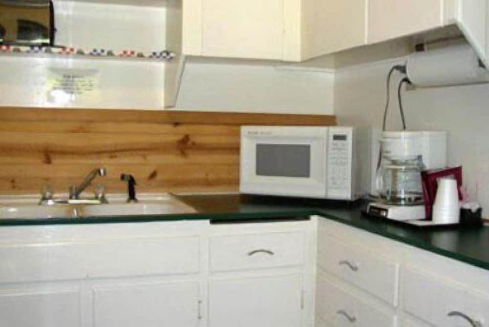 A cozy kitchenette with white cabinets, a wooden backsplash, and appliances like a microwave and blender offers a practical space for travelers seeking self-catering accommodations.