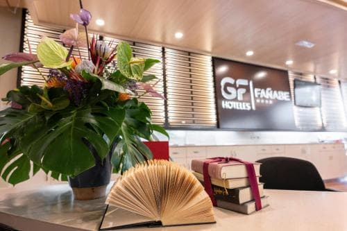 A cozy hotel lobby features vibrant floral arrangements, an inviting desk setup with books, and modern decor, creating a welcoming atmosphere ideal for travelers seeking comfort and relaxation.