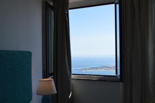 A cozy hotel room with a serene ocean view framed by a large window, perfect for travelers seeking relaxation and scenic beauty.