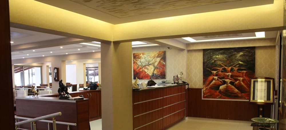 A warmly lit hotel lobby features modern wooden reception desks adorned with vibrant artwork, creating an inviting atmosphere ideal for travelers seeking comfort and style.