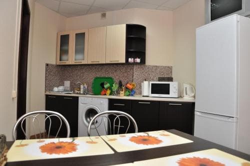 A cozy apartment kitchen with modern appliances, wooden cabinets, and sunflower-themed table mats creates a warm and inviting atmosphere, perfect for travelers seeking a homey stay.