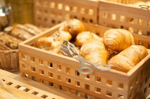 A cozy bakery scene featuring golden croissants nestled in wooden crates, evoking a warm and inviting atmosphere perfect for travelers seeking fresh pastries during their morning exploration.