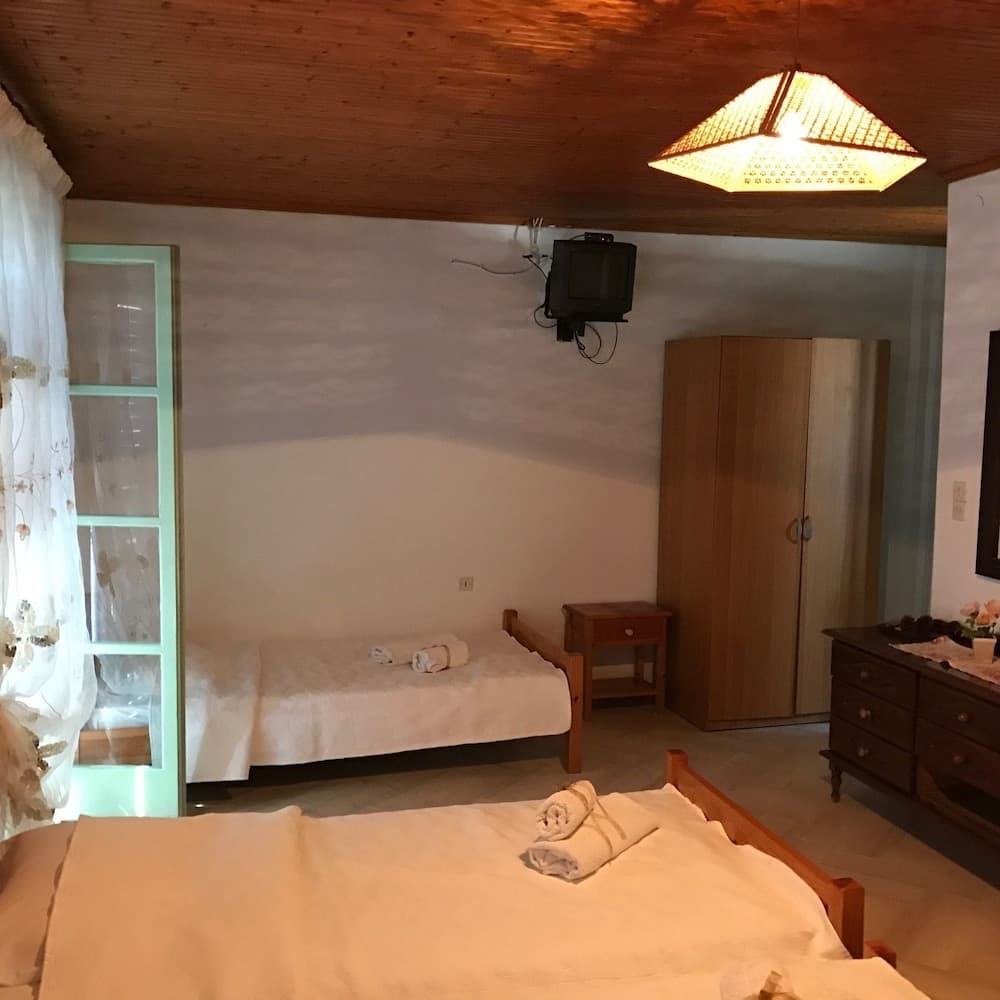 A cozy bedroom with wooden ceilings, neatly arranged beds, and soft lighting creates a warm and inviting atmosphere, ideal for travelers seeking a comfortable retreat.