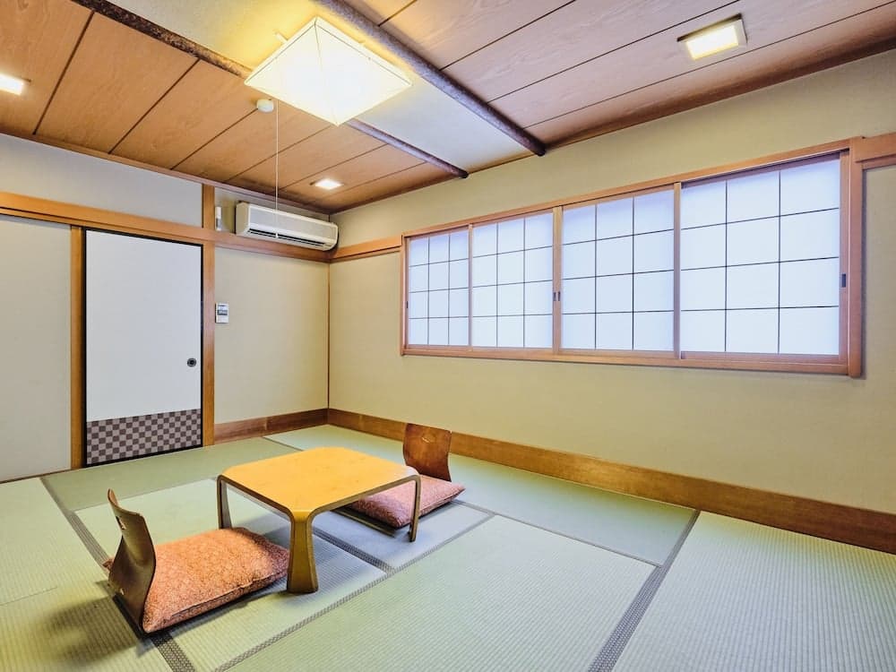 A serene Japanese tatami room with wooden accents, shoji windows, and low seating arrangements offers a tranquil space ideal for meditation or traditional tea ceremonies.