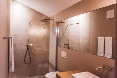 A modern bathroom with sleek glass shower walls, warm lighting, and a large mirror creates an inviting atmosphere, ideal for travelers seeking comfort and style in their accommodations.