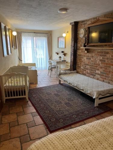 A cozy family-friendly hotel room features brick walls, a crib, a daybed, and a patterned rug, creating a warm and inviting atmosphere ideal for travelers seeking comfort and convenience.