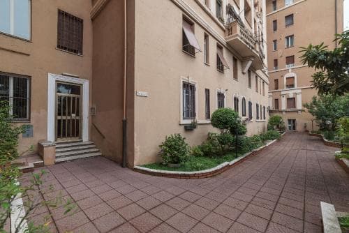 A serene courtyard with tiled pathways, lush greenery, and residential buildings creates an inviting atmosphere ideal for urban travelers seeking a peaceful retreat.