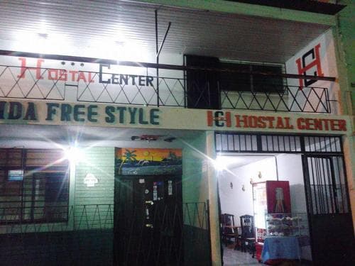 A brightly lit hostel entrance at night features bold signage, inviting travelers to explore its cozy interior filled with furniture and vibrant decor, ideal for budget-friendly accommodations in an urban setting.