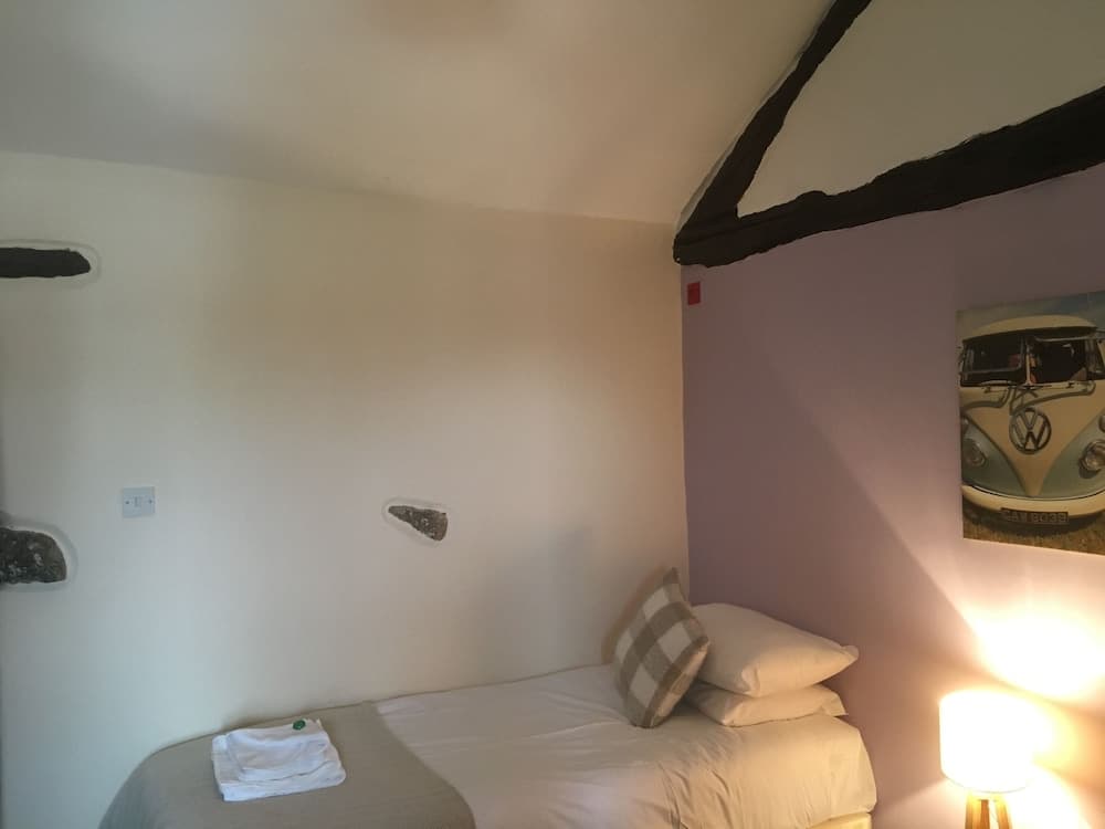 A cozy attic bedroom with exposed beams, soft lighting, and a Volkswagen van poster creates an inviting atmosphere perfect for travelers seeking a quaint and charming accommodation.