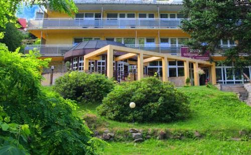 A serene resort building nestled amidst lush greenery offers a tranquil retreat, ideal for travelers seeking relaxation in a picturesque outdoor setting.