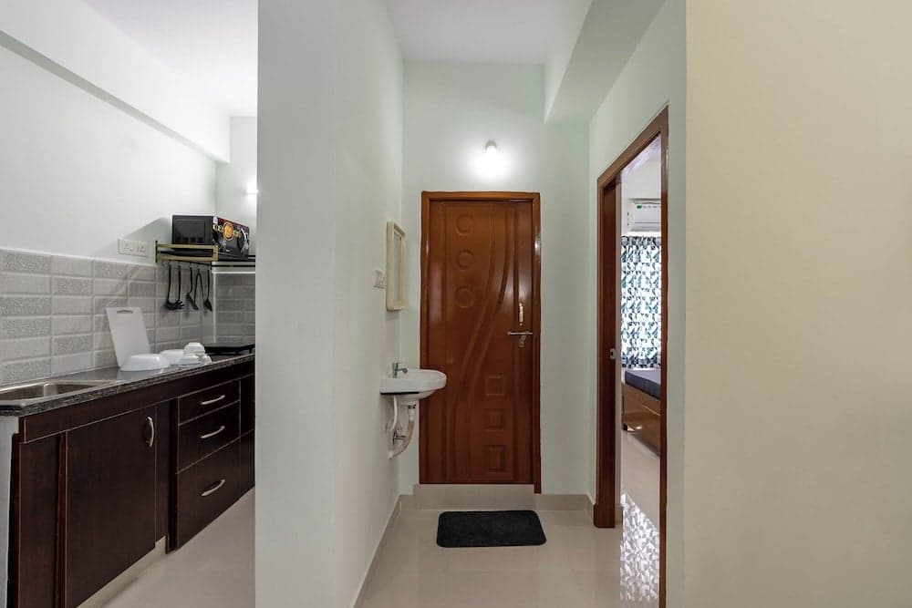 A cozy apartment hallway features a wooden door, small sink, and open kitchen view, creating a welcoming atmosphere ideal for travelers seeking comfortable accommodations.