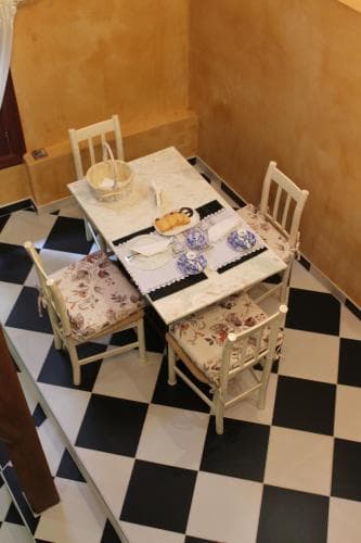 A cozy corner café with a checkered floor, wooden table set for tea with floral-patterned chairs, evokes a charming and inviting atmosphere perfect for a leisurely afternoon escape.