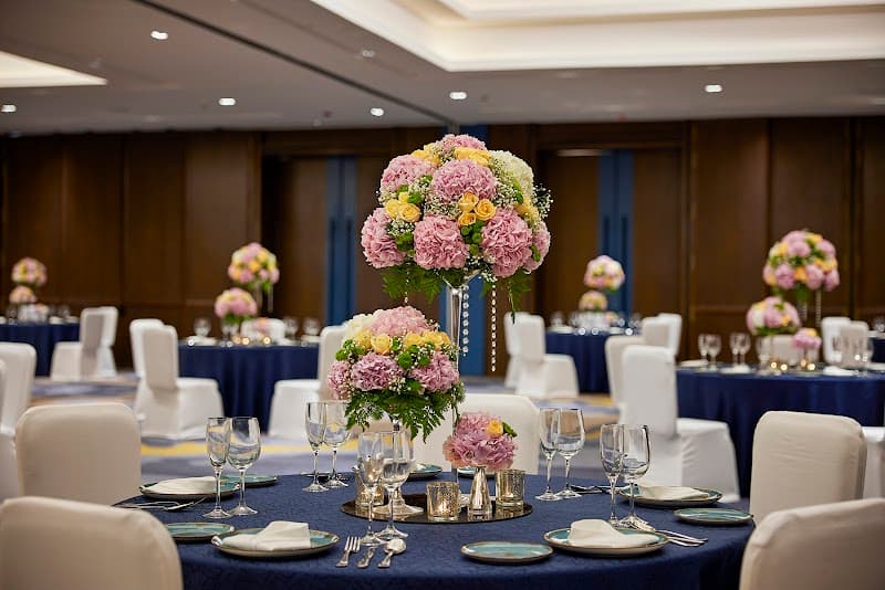 An elegantly set banquet hall at Hyatt Centric Hebbal Bengaluru features tables draped in navy blue linens, adorned with vibrant floral centerpieces, creating a sophisticated ambiance ideal for corporate events or weddings.