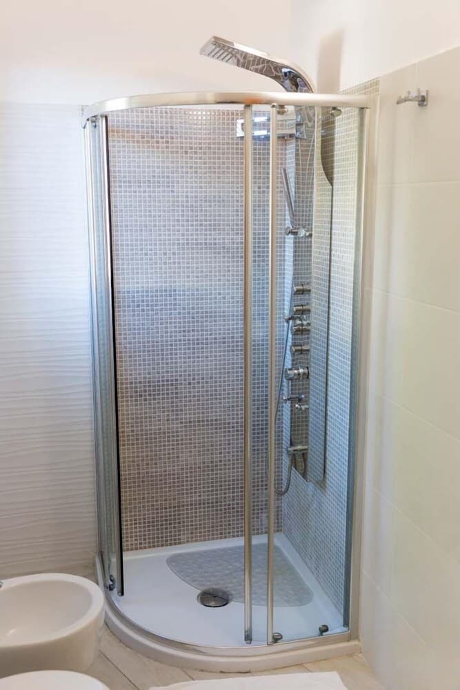 A modern bathroom features a sleek glass-enclosed shower with mosaic tiles, ideal for travelers seeking clean and stylish accommodations.