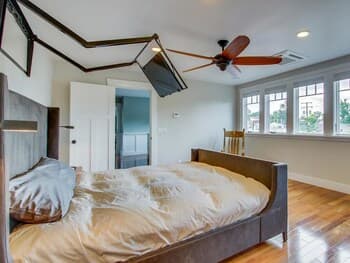 A cozy bedroom with a plush bed, wooden floors, and large windows inviting natural light creates a serene retreat, ideal for travelers seeking relaxation and comfort.