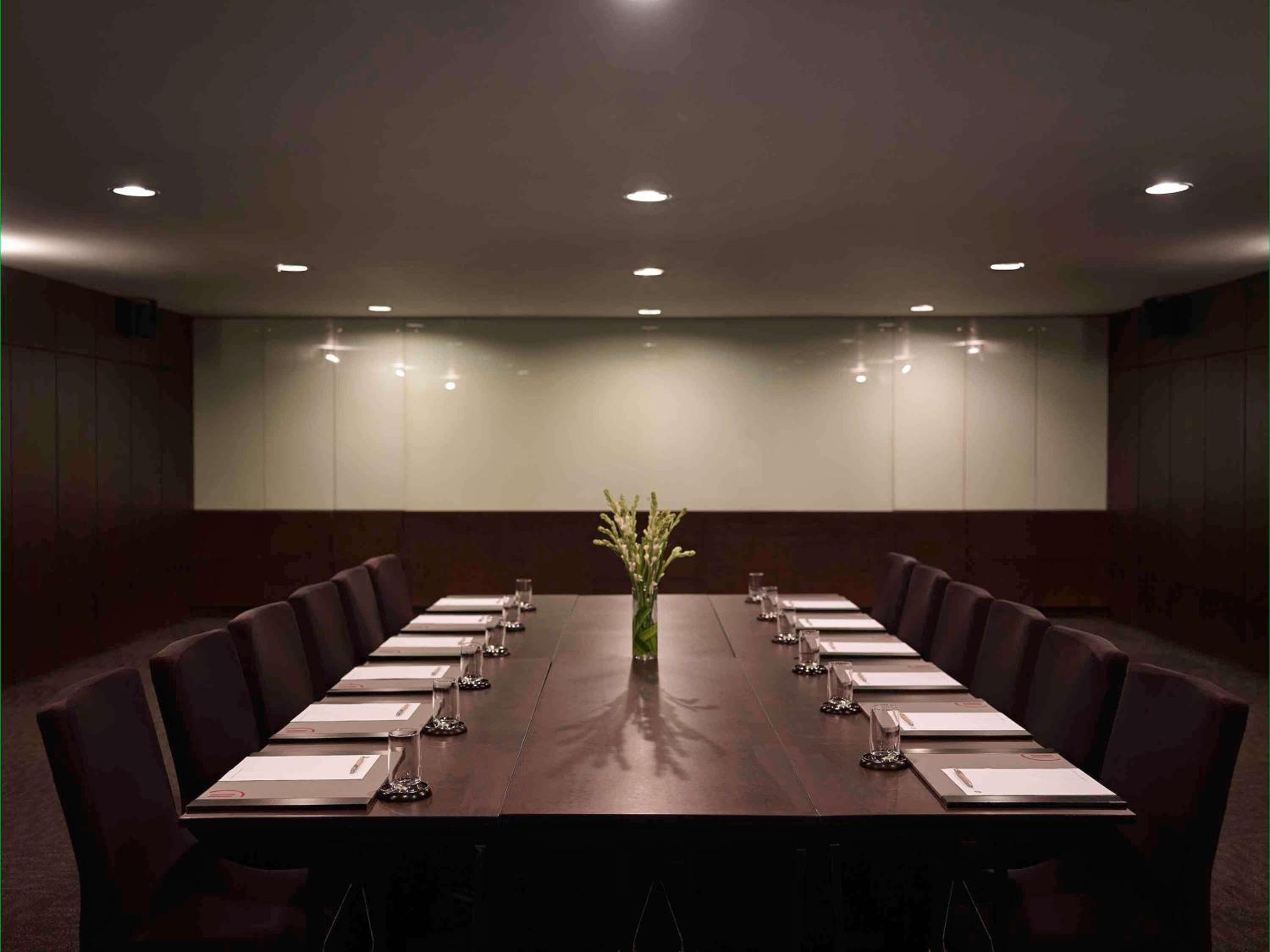 A modern conference room with a sleek wooden table, chairs, and minimalistic decor creates a professional atmosphere ideal for business travelers seeking a focused meeting space.