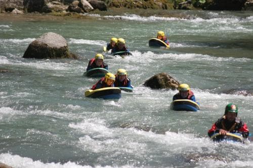 Thrill-seekers navigate the turbulent waters of a river rapids scene, enjoying an adventurous group tubing experience amidst rocky surroundings, perfect for outdoor enthusiasts seeking excitement.