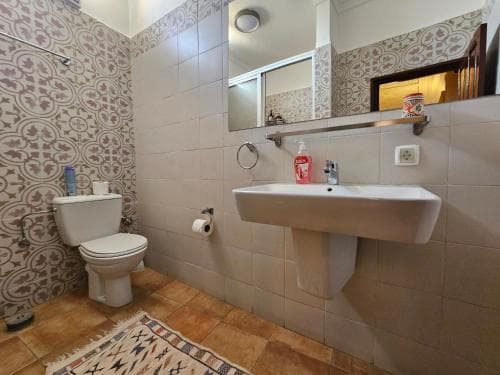 A cozy bathroom with patterned tiles, a sink, toilet, and mirror, featuring a decorative rug on the floor, ideal for travelers seeking comfort in compact accommodations.