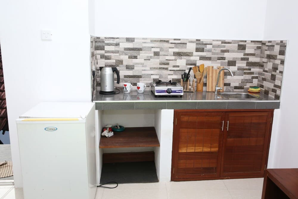 A cozy kitchenette with a mosaic-tiled backsplash, wooden cabinets, and essential appliances creates a welcoming atmosphere ideal for travelers seeking self-catering accommodations.