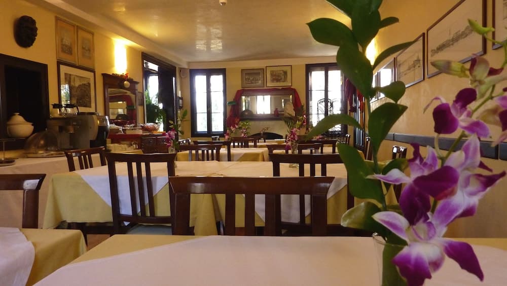 A cozy restaurant with warm lighting, wooden furniture, and vibrant orchids creates an inviting atmosphere perfect for travelers seeking a charming dining experience.