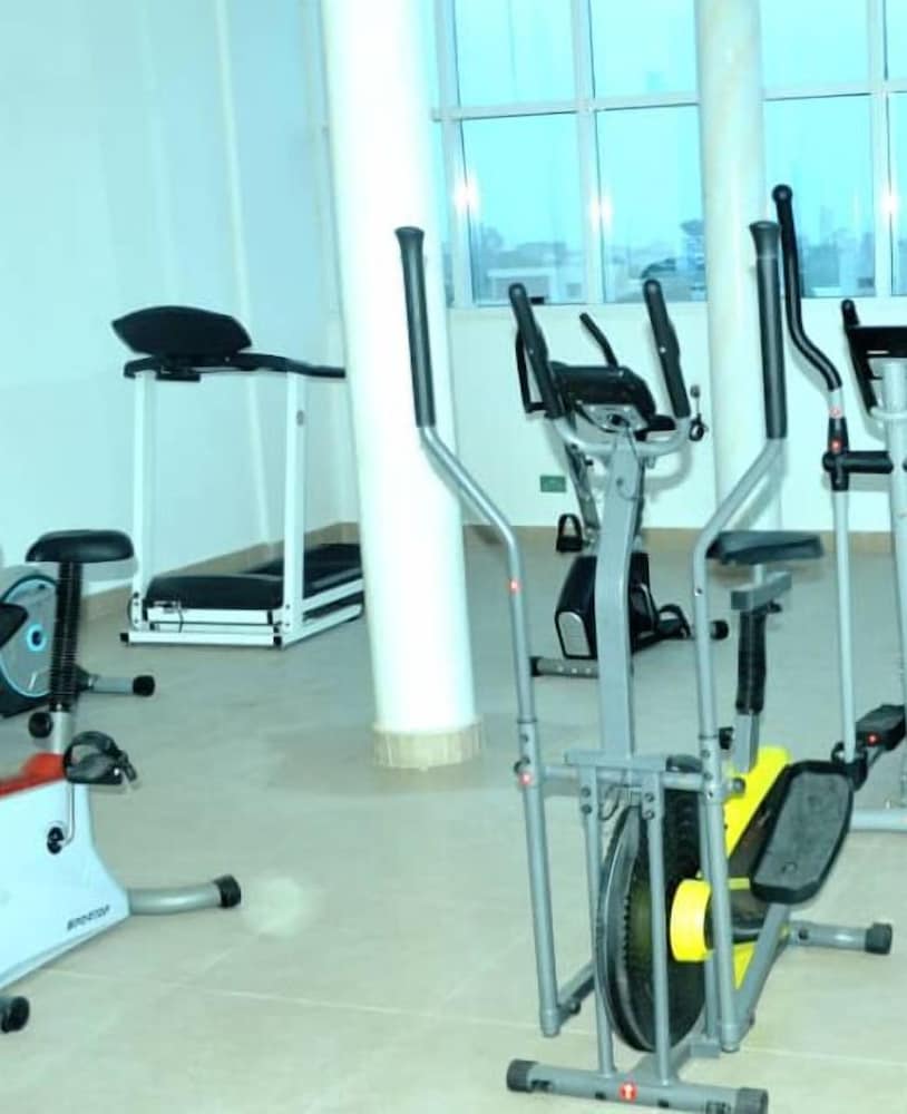 A well-lit indoor gym features various exercise machines like ellipticals and stationary bikes, creating an inviting atmosphere for fitness enthusiasts seeking a space to maintain their health routines.
