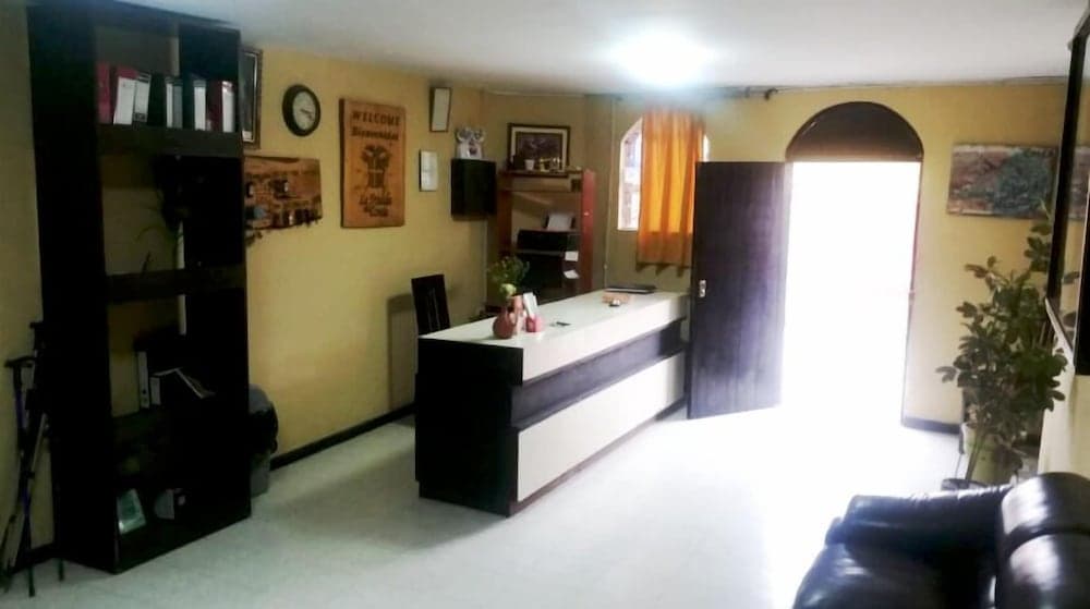 A cozy hotel lobby with warm yellow walls, a welcoming reception desk, and comfortable seating exudes a relaxed atmosphere, ideal for travelers seeking a peaceful stay.