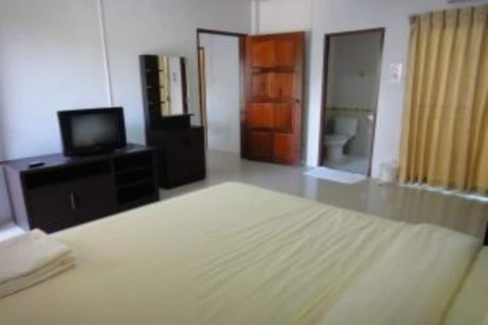 A cozy hotel room features a neatly made bed, a TV on a dark wooden stand, and an en-suite bathroom visible through an open door, ideal for travelers seeking comfort and convenience.