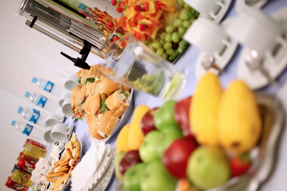 A vibrant buffet table laden with fresh fruits, sandwiches, and beverages creates an inviting atmosphere ideal for a business meeting or conference refreshment setup.