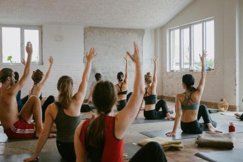 A serene yoga studio with participants in upward-facing dog pose, surrounded by natural light from large windows, evokes a tranquil atmosphere ideal for wellness retreats and mindfulness workshops.
