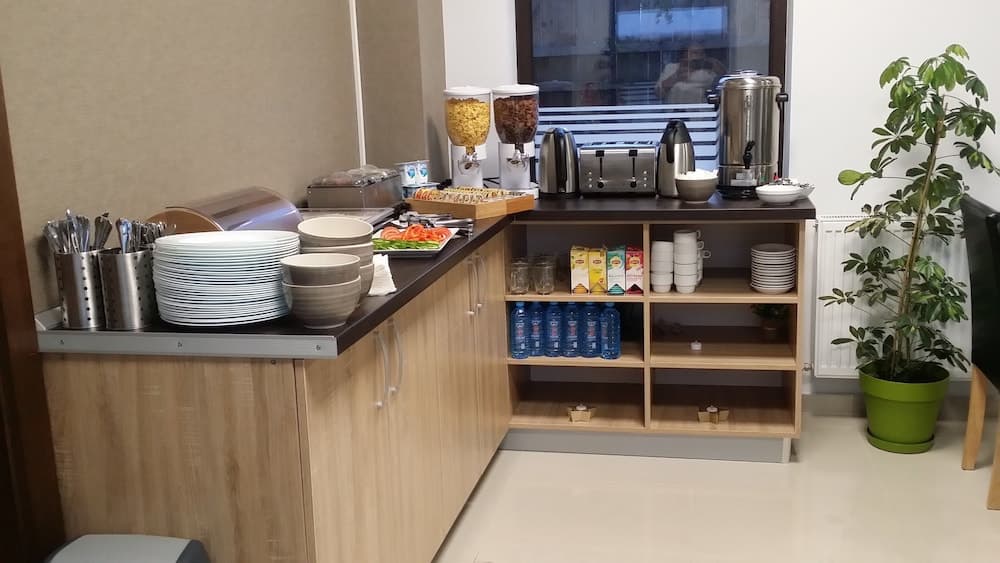 A cozy hotel breakfast nook features a well-stocked buffet counter with cereals, fresh fruit, beverages, and neatly arranged dishes, creating an inviting atmosphere for travelers seeking convenience and comfort.