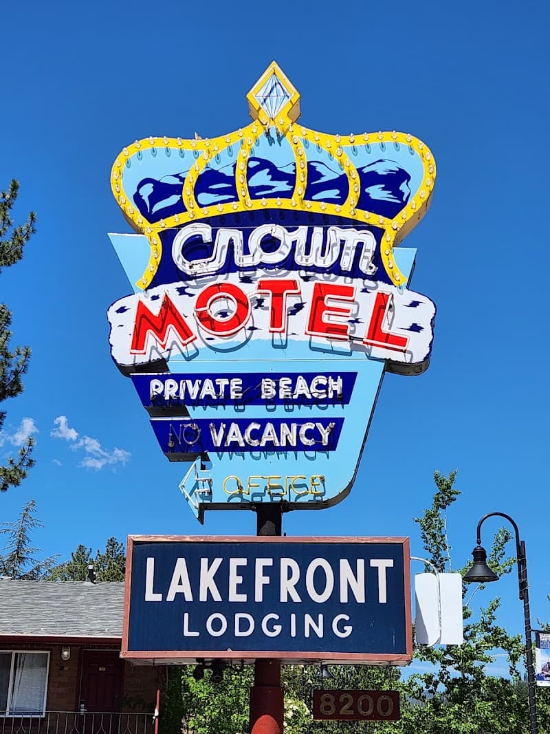 A vibrant retro sign for the Crown Motel in Kings Beach, California, advertises lakefront lodging with a private beach under a clear blue sky, perfect for travelers seeking a nostalgic and relaxing getaway.