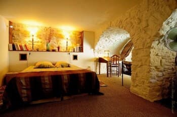 A cozy bedroom with rustic stone walls, warm lighting, and artistic decor creates an inviting atmosphere, perfect for travelers seeking a unique and intimate accommodation experience.