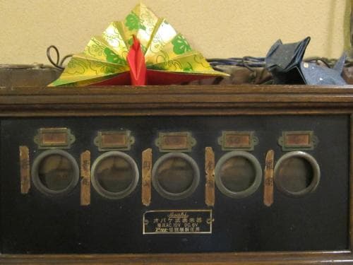 A vintage wooden fortune-telling machine adorned with colorful origami sits in a nostalgic indoor setting, ideal for cultural exploration and unique souvenir hunting.