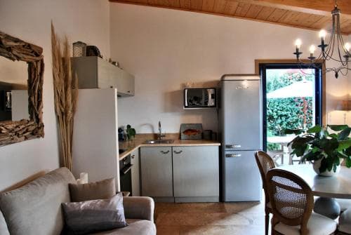 A cozy kitchen-living area with modern appliances, a rustic chandelier, and an inviting outdoor patio view through glass doors, perfect for a relaxing vacation rental experience.