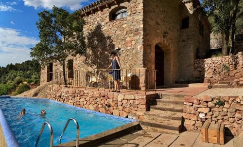 A serene rural retreat features a rustic stone villa with a vibrant blue pool, surrounded by lush greenery, ideal for a tranquil vacation escape.