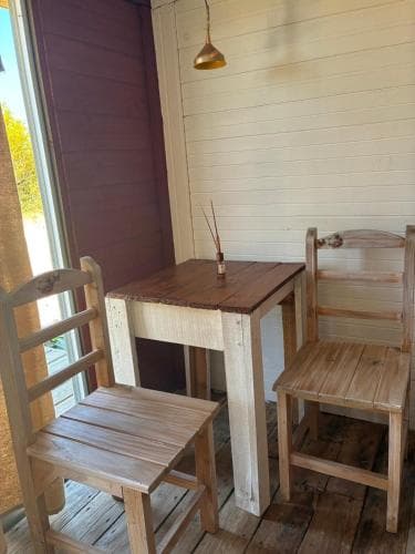 A cozy indoor dining nook features rustic wooden chairs and a table by a window, set against warm-toned walls, ideal for intimate gatherings or a quiet retreat during a vacation.