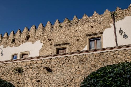 A historic stone wall with battlements under a clear blue sky evokes a serene medieval atmosphere, ideal for travelers exploring cultural heritage sites.