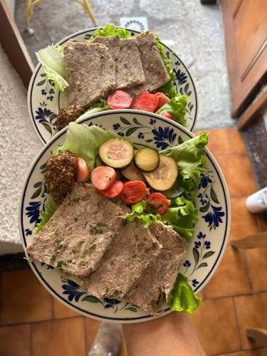A cozy indoor setting features two ornate plates filled with fresh salads and slices of seasoned meat, perfect for a culinary traveler seeking authentic local dining experiences.