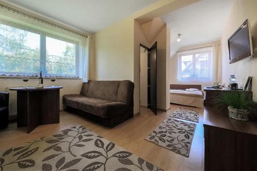 A cozy apartment interior featuring a living area with a sofa, dining table, and bedroom in the background, ideal for travelers seeking comfort and convenience in a compact space.
