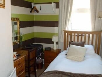 A cozy bedroom with striped green and white walls, wooden furniture, and soft lighting creates a serene atmosphere, ideal for travelers seeking a peaceful retreat.