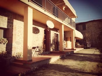 A rustic stone villa with a sunny patio, wooden chairs, and satellite dishes exudes a cozy, countryside charm ideal for tranquil retreats.