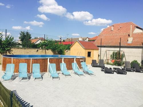 A serene backyard pool area features turquoise lounge chairs under a clear blue sky, ideal for relaxing summer getaways in a cozy residential setting.