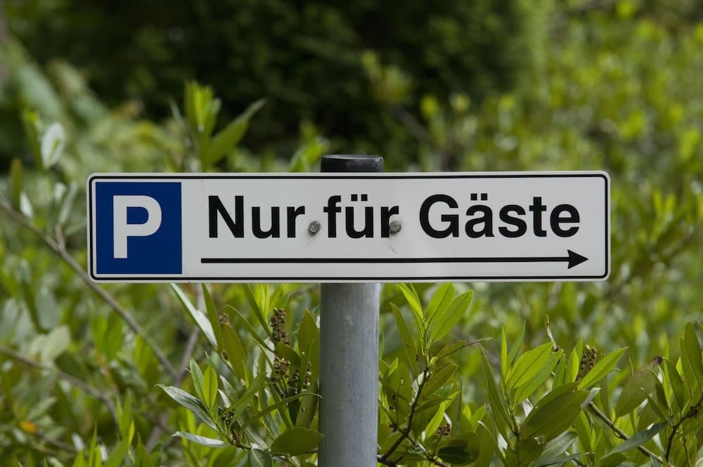 A serene park setting features a clear "Nur für Gäste" parking sign amidst lush greenery, ideal for travelers seeking guest-specific parking directions in German-speaking regions.