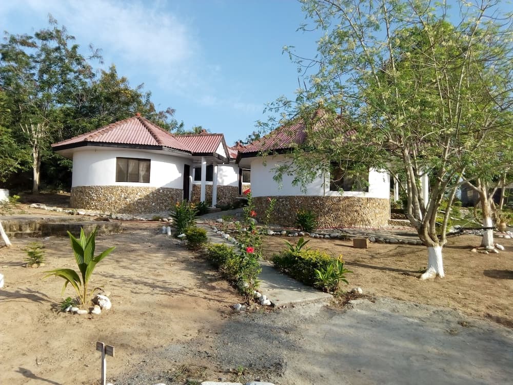 A serene rural retreat features charming stone-and-white cottages nestled among lush greenery, ideal for travelers seeking a peaceful countryside escape.