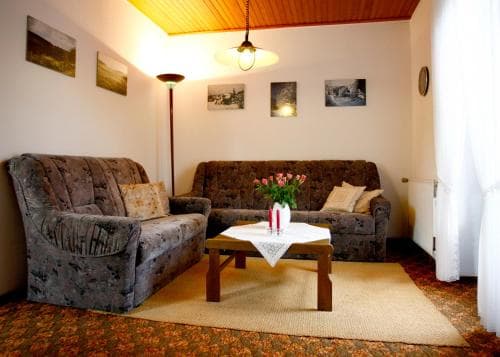 A cozy living room with plush sofas, framed artwork, and warm lighting creates an inviting atmosphere, perfect for travelers seeking a comfortable and homely accommodation experience.