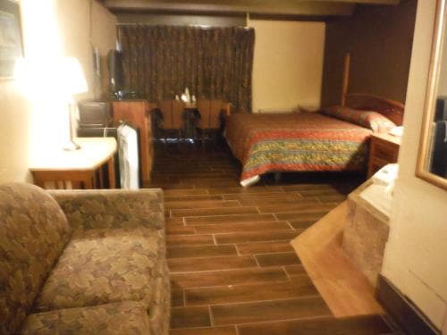 A cozy hotel room with warm lighting, patterned furniture, and a brick-tiled floor creates an inviting atmosphere, perfect for travelers seeking comfort and relaxation.