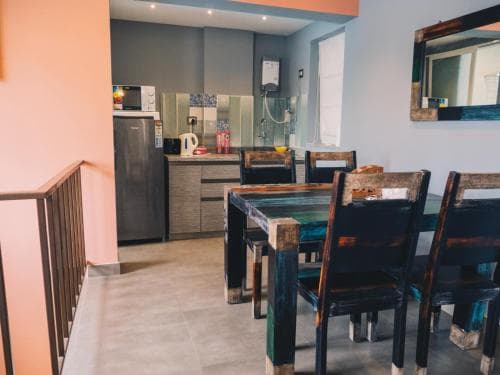 A cozy dining area with wooden chairs around a rustic table, set in a modern kitchen with tiled floors, ideal for travelers seeking a homey and functional rental space.