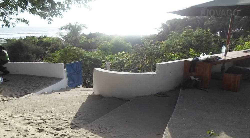 A serene beachside seating area with white concrete benches overlooks lush greenery and the ocean, perfect for travelers seeking relaxation and scenic views.