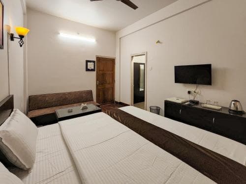 A cozy hotel room features two neatly made beds, a sleek TV console, and warm lighting, creating an inviting atmosphere ideal for travelers seeking comfort and relaxation.