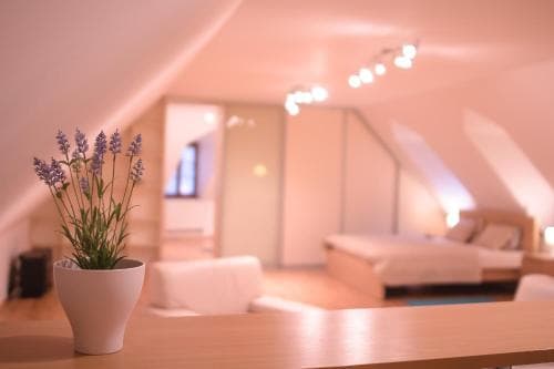A cozy attic bedroom with soft lighting, a neatly made bed, and a lavender plant on the desk creates a serene atmosphere ideal for relaxation and travel accommodation searches.